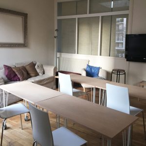 salle de réunion avec des tables et des chaises disposées vers un écran