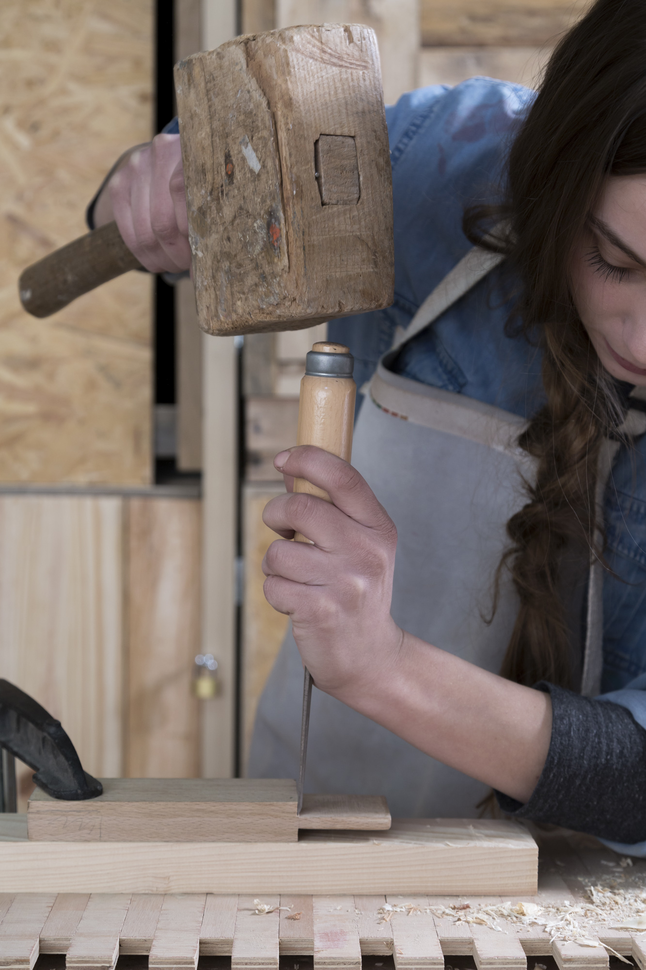 une femme utilisant des outils pour travailler un morceau de bois dans un établi