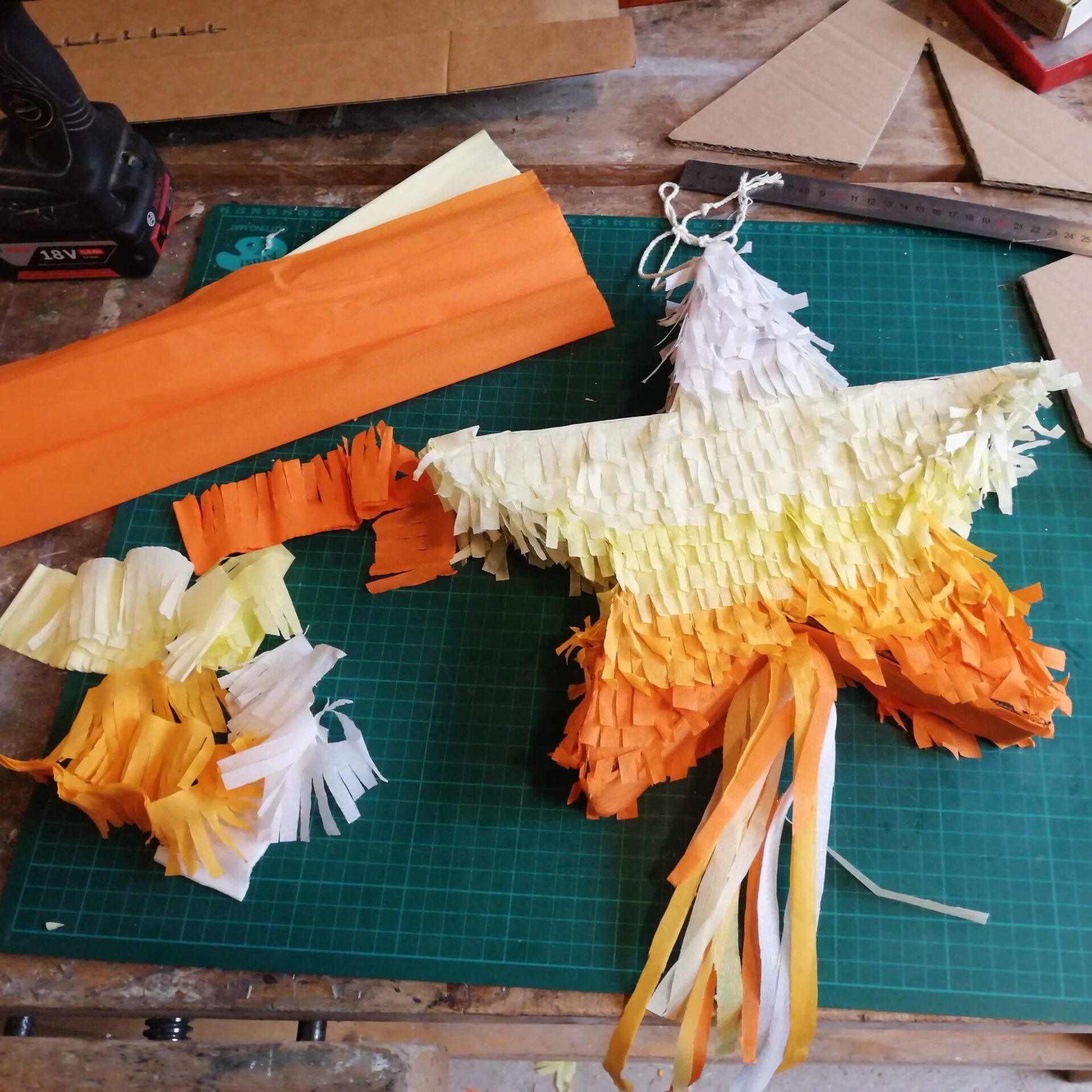 une pinata en forme d'étoile orange, jaune et blanche en papier posée sur une table