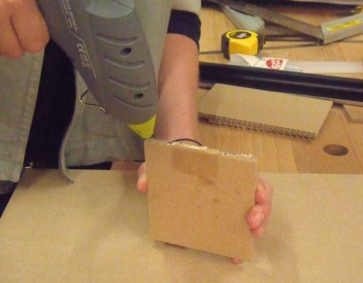 quelqu'un en train de coller un morceau de carton avec un pistolet à colle