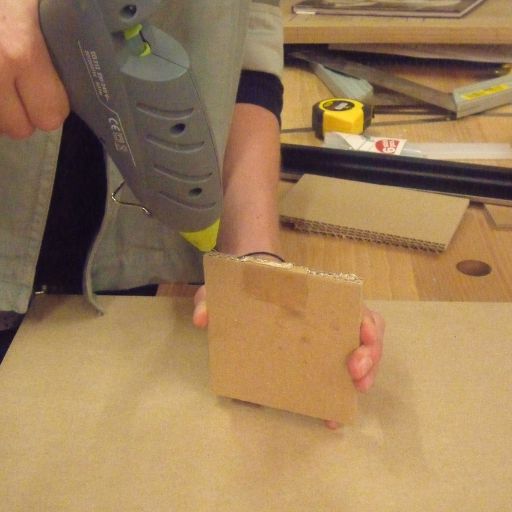 quelqu'un en train de coller un morceau de carton avec un pistolet à colle