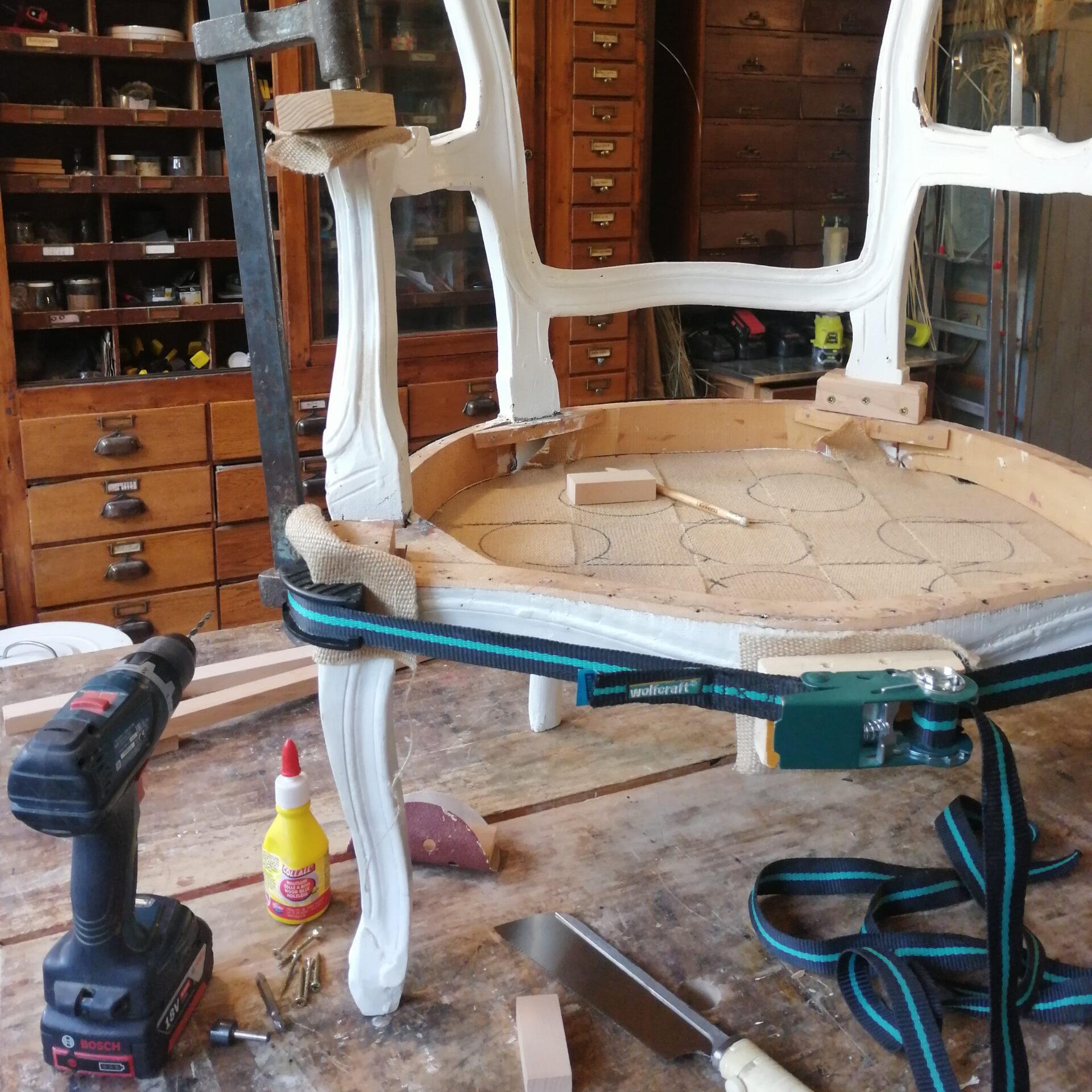 siège en bois en train d'être réparé avec de la colle et des outils