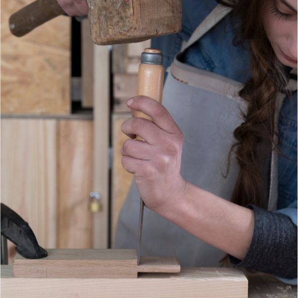 une femme en train d'utiliser des outils pour couper du bois