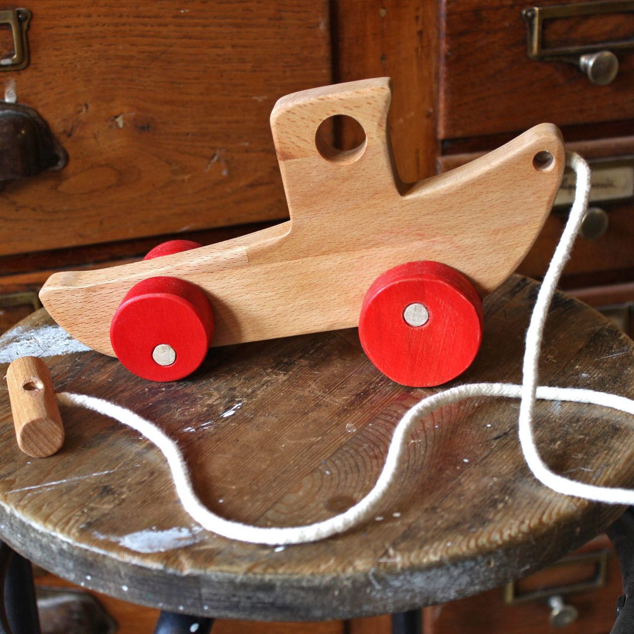 jouet en bois avec une ficelle posé sur un tabouret